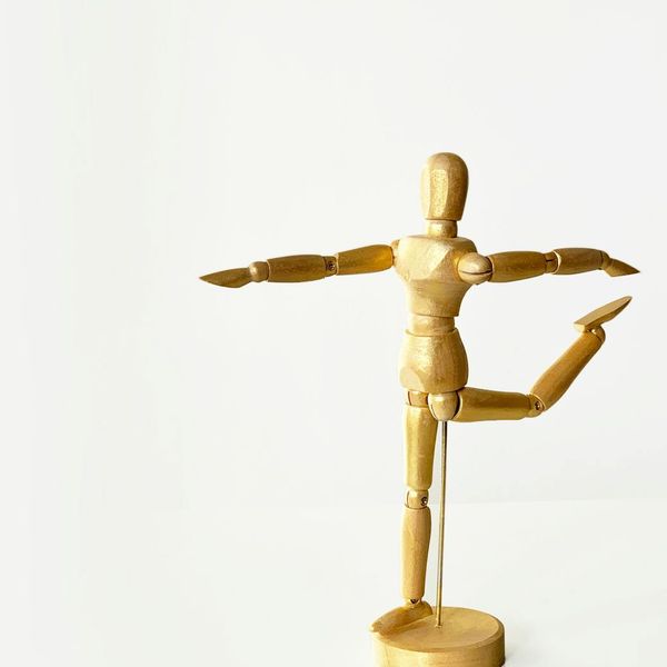A person demonstrating a strong warrior yoga pose against a minimal background.